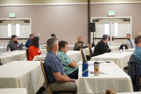 Seated audience with one person in the middle gesturing while talking.