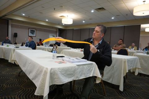 A man holds a yellow rectangle pavement marker to see the markings.