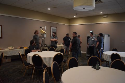A group of men talk to one another next to a buffet table.