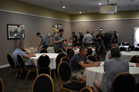 A group of people talk to one another. Some are in line at a buffet table and others are seated.