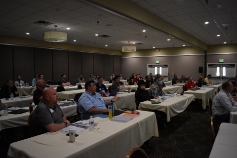 A man sitting in an audience raises his hand and speaks.