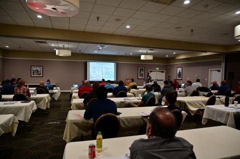 A seated audience watches a man present.