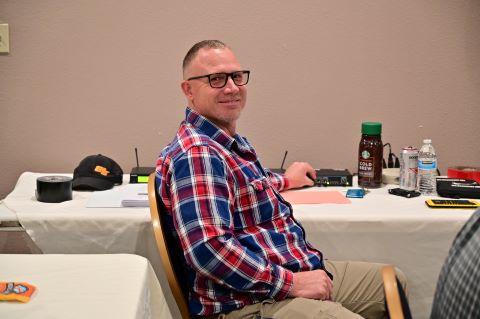 A man poses for a photo next to a table with sound equipment on it.