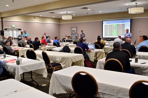 A man raises his hand while seated in the audience.