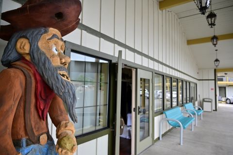A wooden statue of a miner stands next to a building.