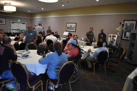 Several groups of people talk to one another while seated at tables.
