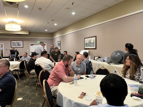 Several groups of people talk to one another while seated at tables.