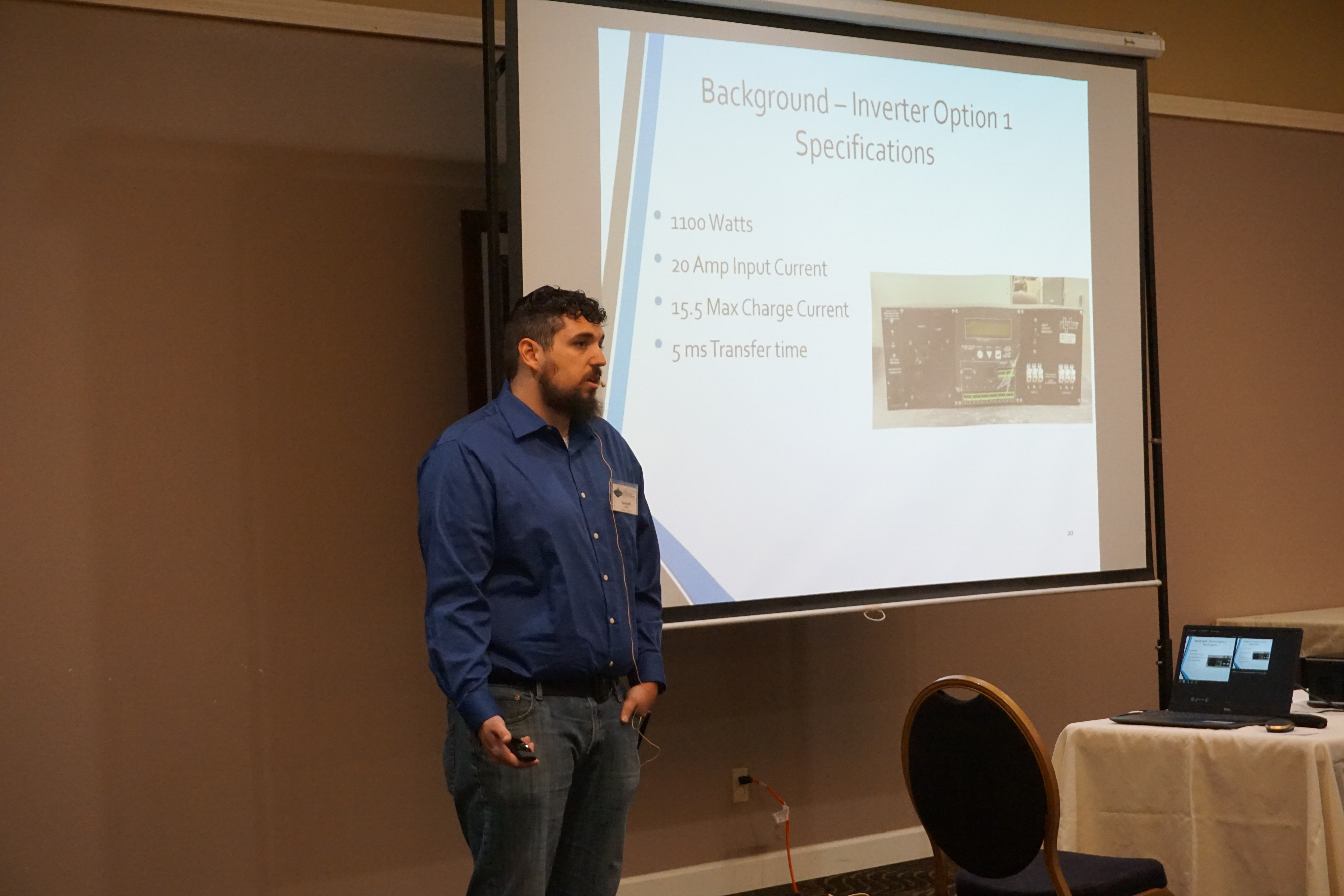 A man stands to the left of projector screen showing a slide titled 
