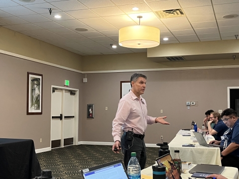 A man gesturing with both hands while speaking to an audience.